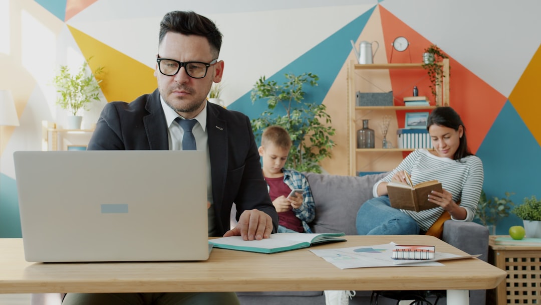 Vrouw werkt op laptop terwijl gezin op de achtergrond