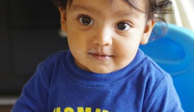 A baby in a blue shirt with yellow text.