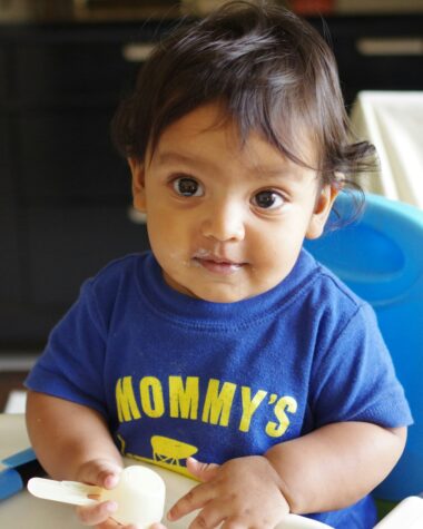 A baby in a blue shirt with yellow text.