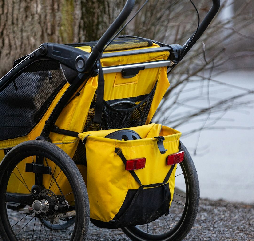 A yellow stroller parked next to a tree