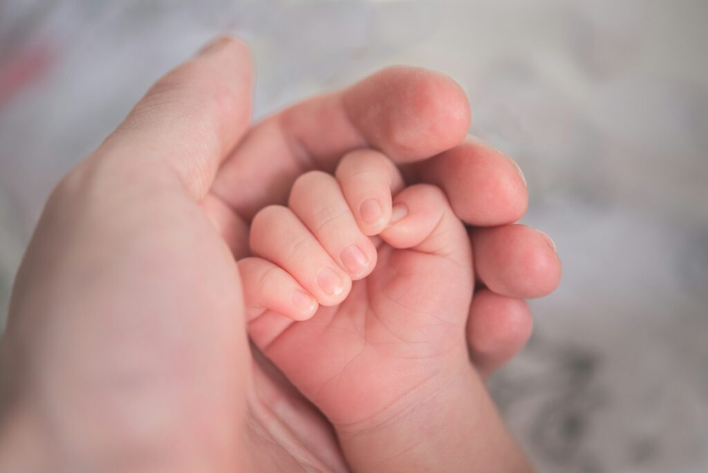 Babyhandje dat de vinger van een ouder vasthoudt