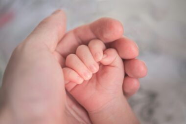 Babyhandje dat de vinger van een ouder vasthoudt