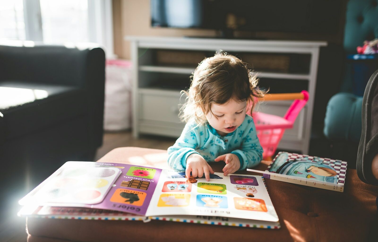 Ouder leest een prentenboek voor aan een kind op de bank