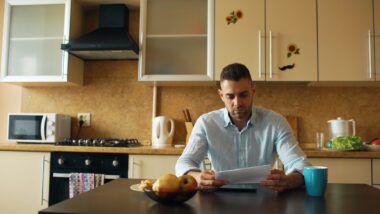 Moeder aan de keukentafel met papieren en een laptop