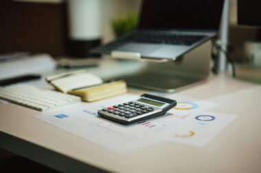 Ouder rekent aan de keukentafel met een laptop en papieren de opvangkosten uit
