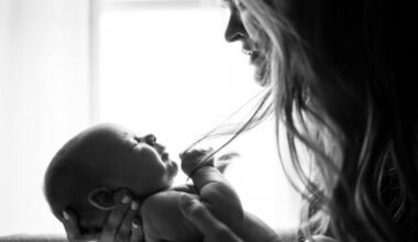 Moeder zit vermoeid met haar baby op de arm bij het raam