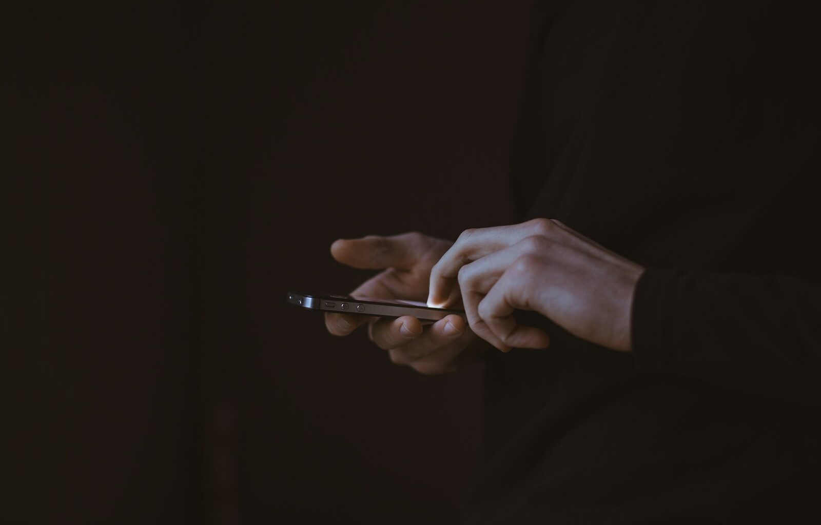 Handen van een tiener met een smartphone in het donker