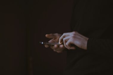 Handen van een tiener met een smartphone in het donker