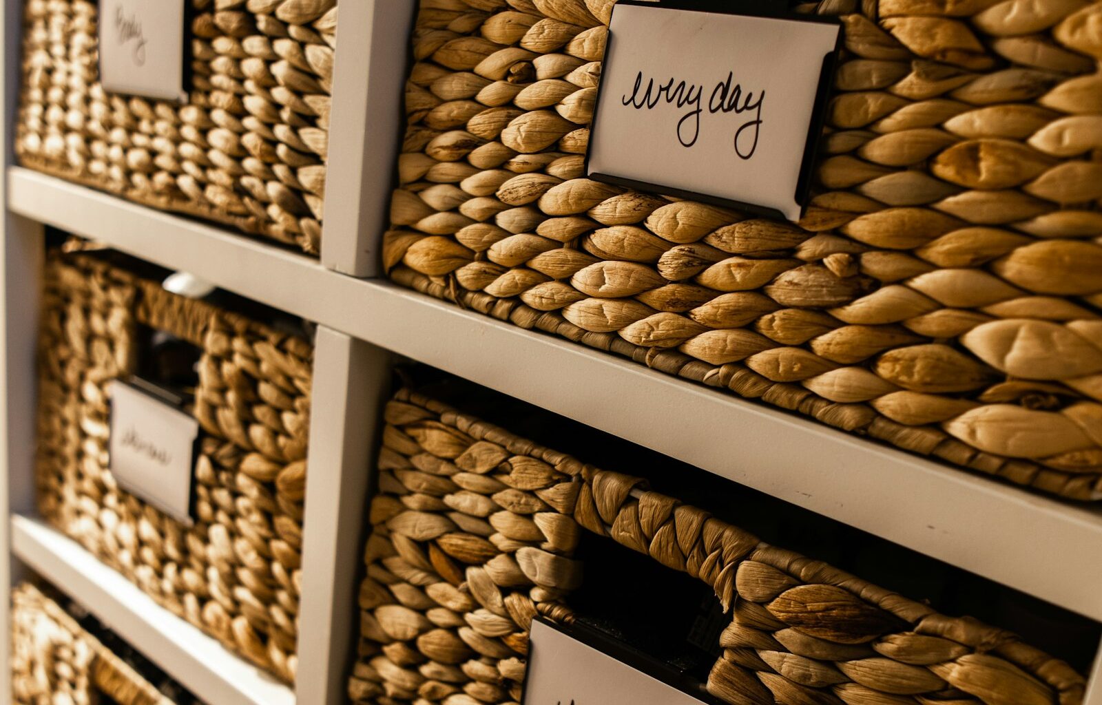 Rieten opbergmanden met labels in een kast