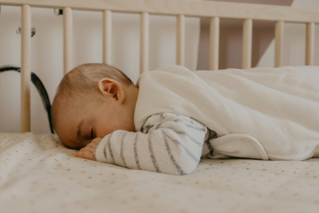 Baby slaapt in een slaapzak in een ledikant