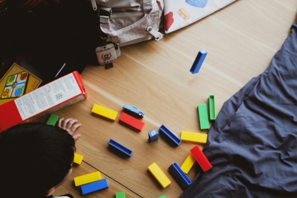 Kind speelt met blokken op een houten vloer