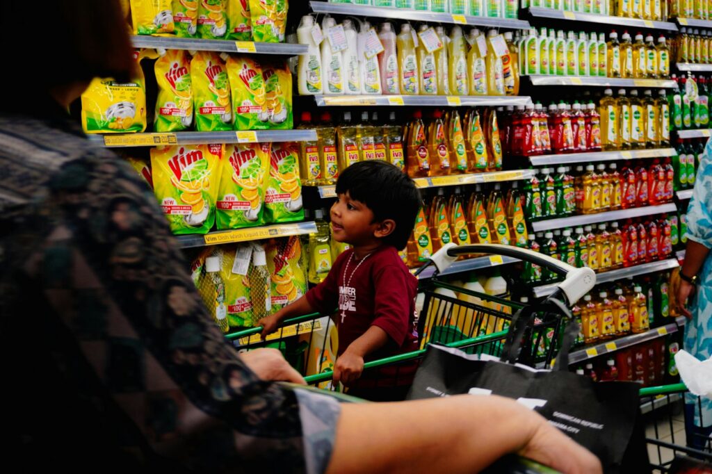 Moeder met boodschappenkar en kind in het gangpad van de supermarkt