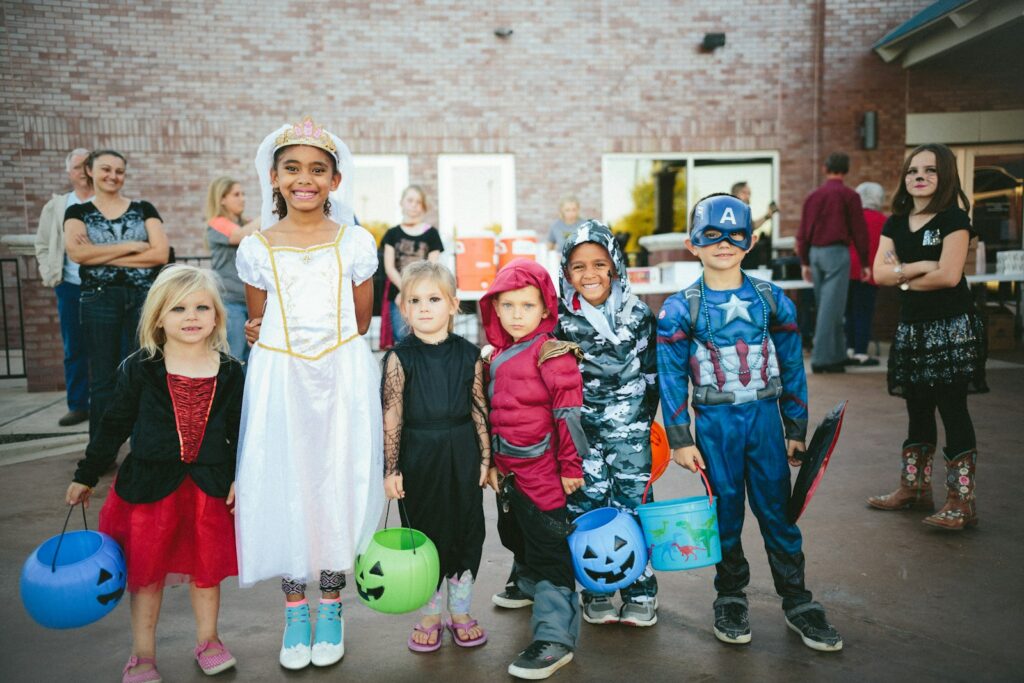 Kinderen in halloweenkostuum met een pompoenemmer bij een voordeur