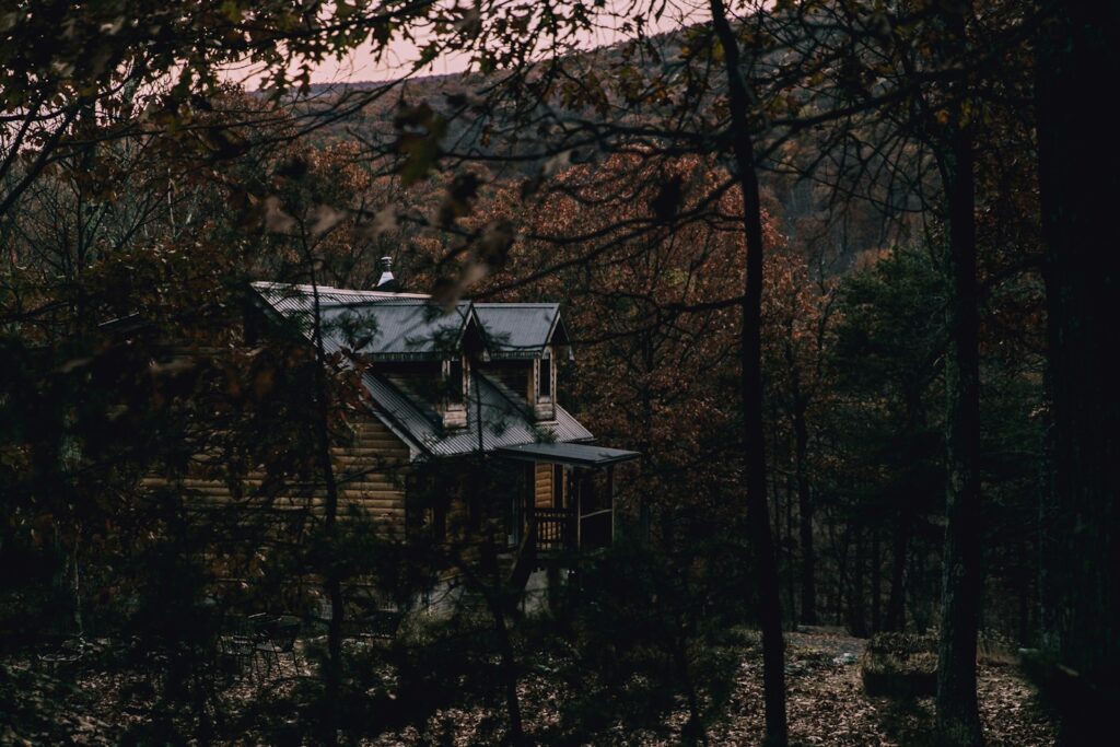 Gezin met jonge kinderen in regenjassen bij een vakantiehuisje in het herfstbos
