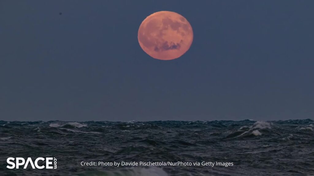 Oranje volle maan die opkomt boven een woelige zee