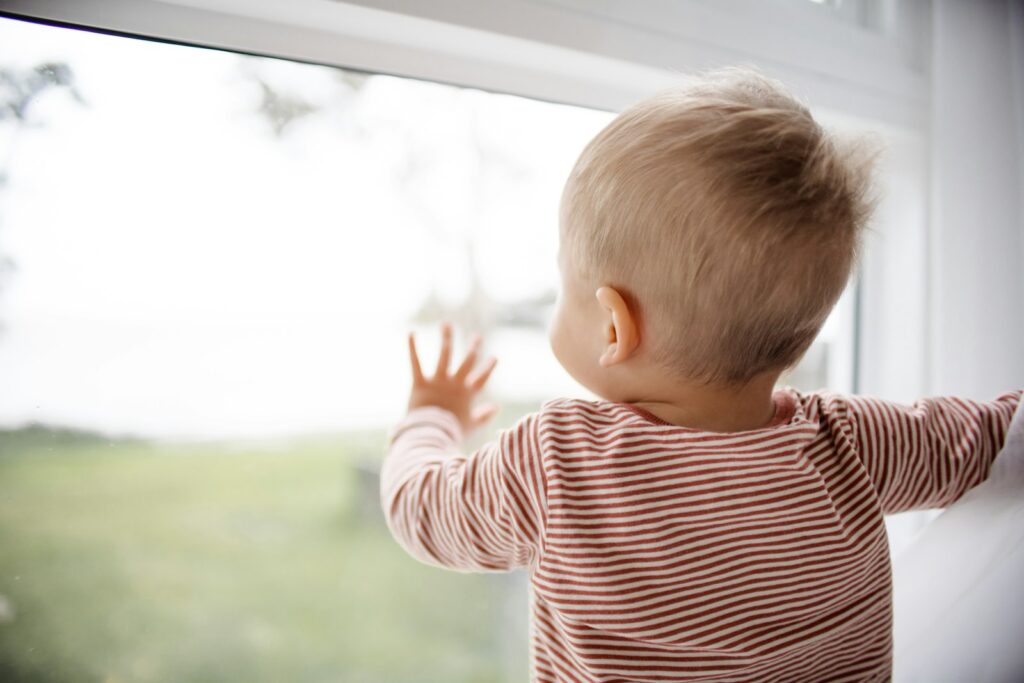 Peuter zwaait naar zijn moeder bij de deur van het kinderdagverblijf