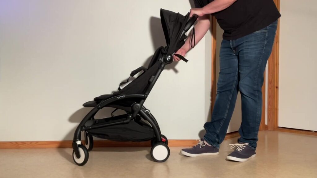 Ouder klapt een zwarte Stokke YOYO kinderwagen in