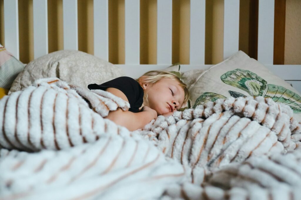 Kind slaapt in bed met een knuffel