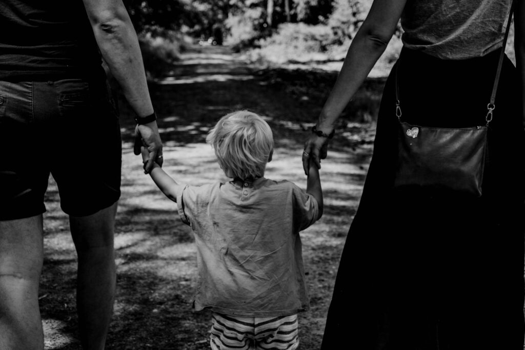 Ouders lopen met hun enige kind tussen hen in door het park