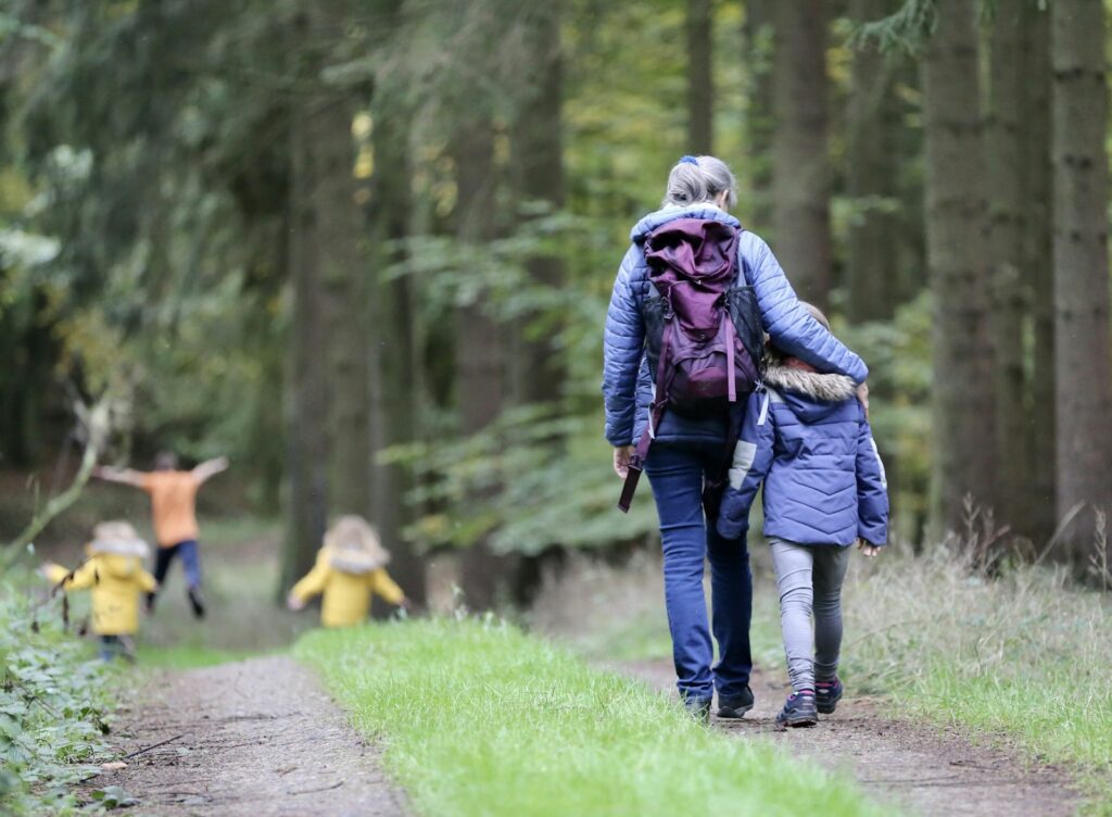 Moeder en kinderen wandelen samen door het herfstbos