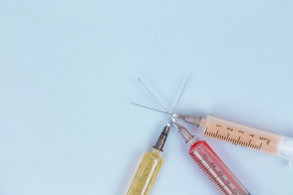 Injectiepen en naald op een tafel naast een smartphone