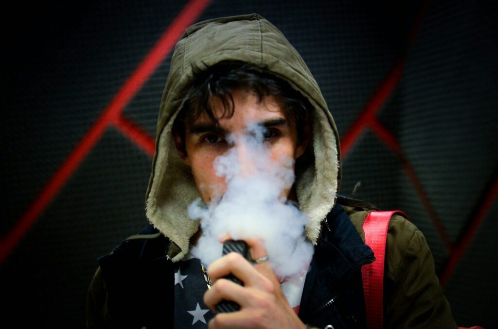 Tiener met een vape in de hand, buiten op straat