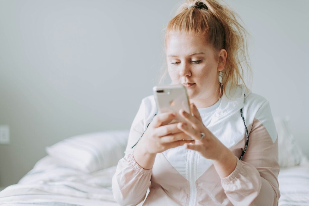 Zwangere vrouw op de bank met haar telefoon in de hand