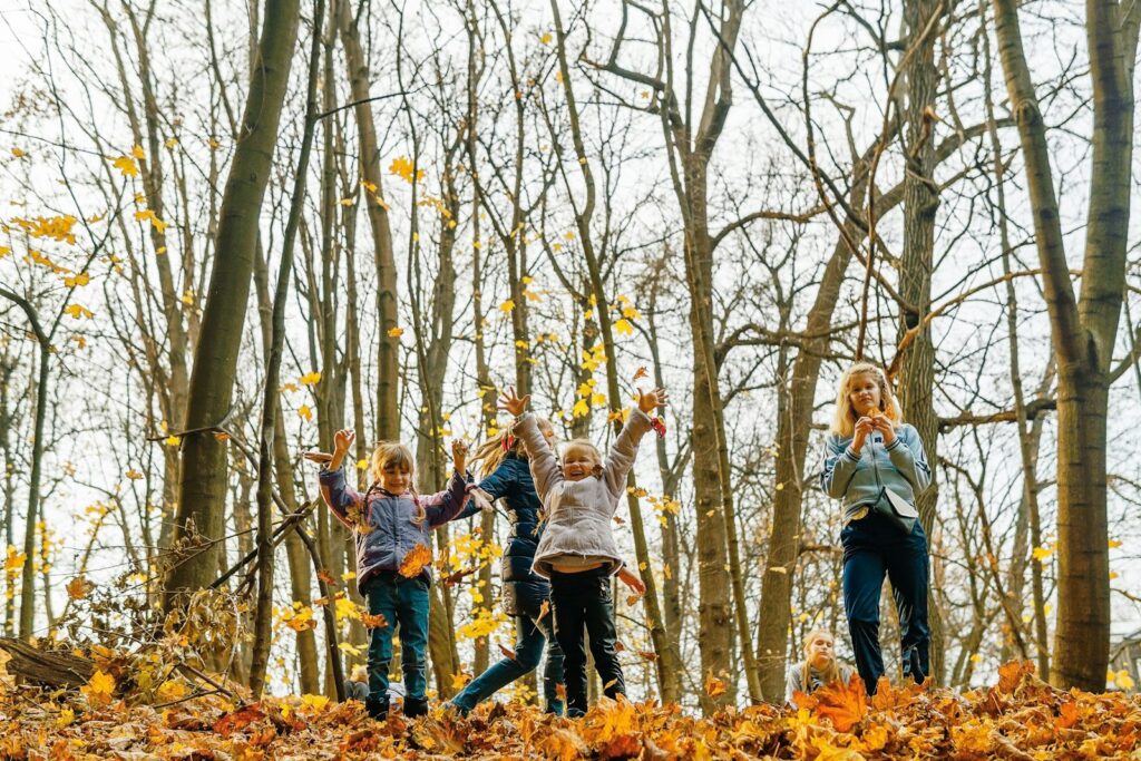Ouder en kinderen wandelen door een zonnig herfstbos